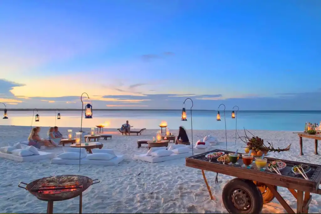 A candlelit dinner table set on the beach at sunset