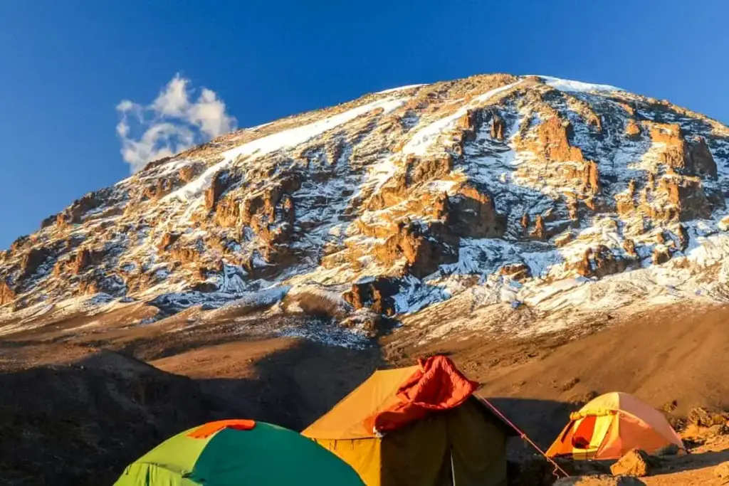 Colourful tents below the snowy dome of Kilimanjaro