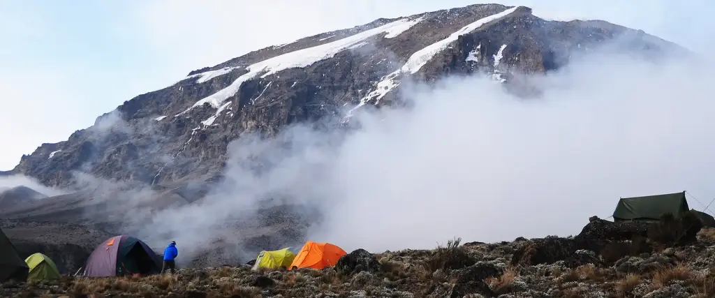 Tents at a high camp as clouds drift over Kilimanjaro