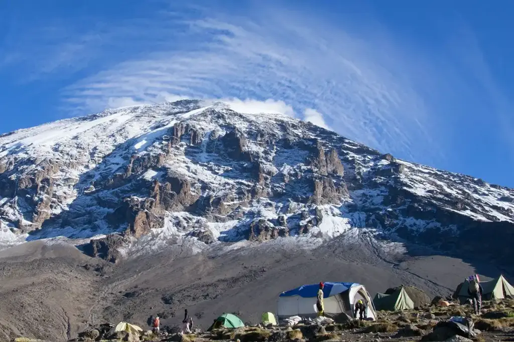 The snowy summit of Kilimanjaro above a camp of tents