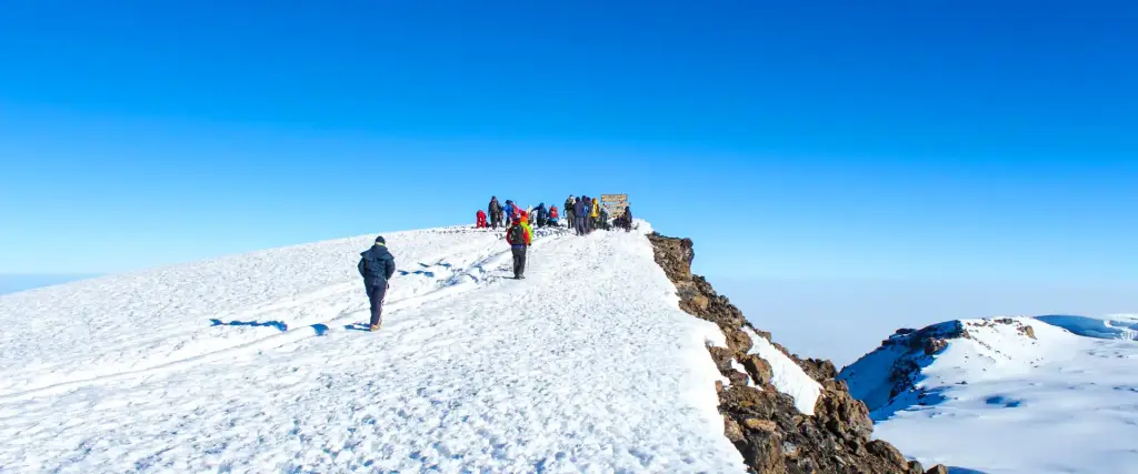 Climbers on a snowy ridge under a blue sky
