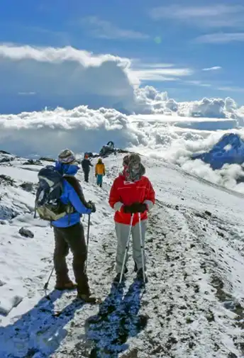 Climbers walking up a snowy trail on Kilimanjaro