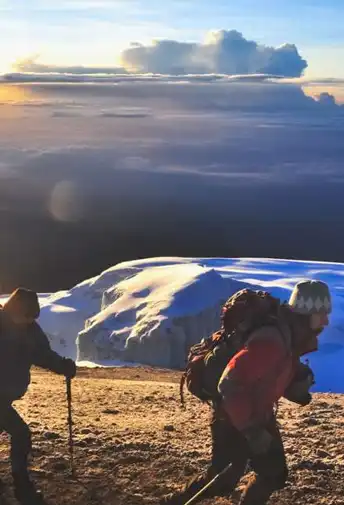 A climber carrying a pack at dawn on Kilimanjaro